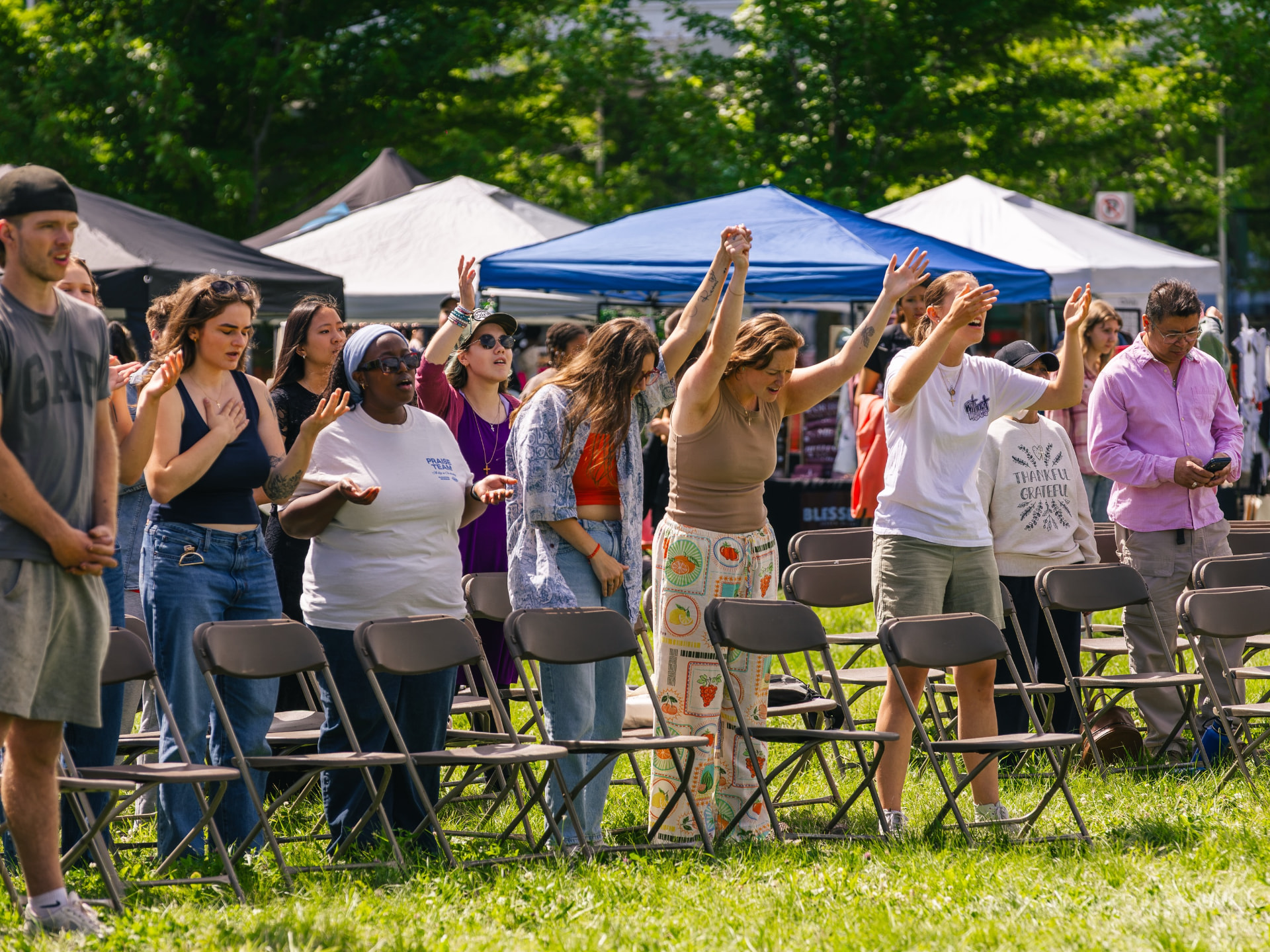People worshipping with hands raised at an outdoor gathering