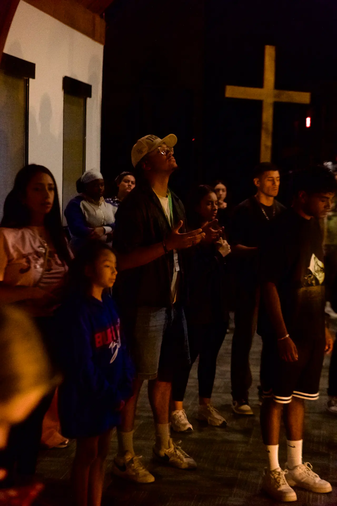 The room standing in worship beneath the wooden cross at a Souled Out night