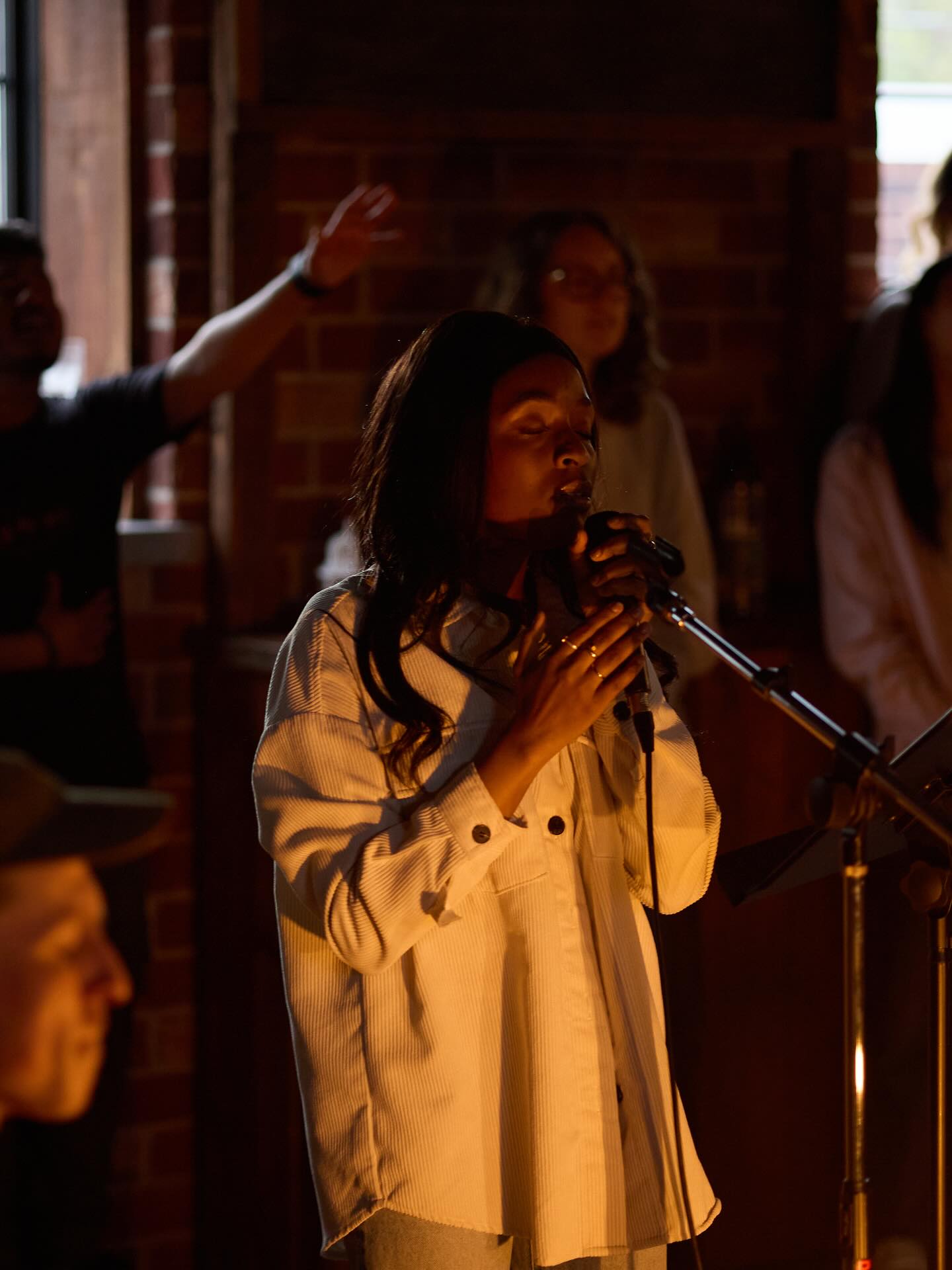 A worship leader singing in warm candlelight