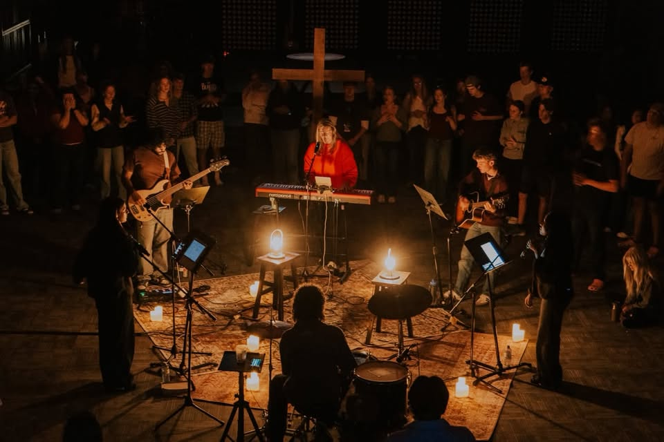 The worship team leading by candlelight with a cross behind them